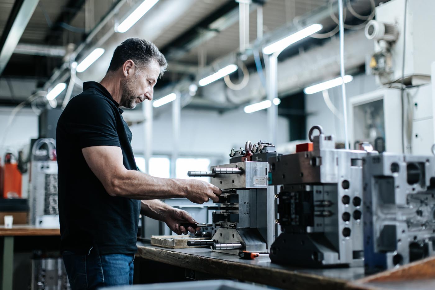 PHOTO D'UN PROFESSIONNEL ENTRAIN DE RÉALISER LA MAINTENANCE D'UN MOULE INDUSTRIEL POUR INJECTION PLASTIQUE